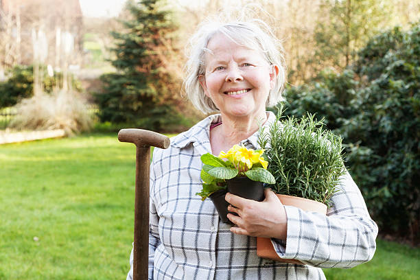 allegro donna anziana giardinaggio pronto per la primavera - women large build gardening outdoors foto e immagini stock