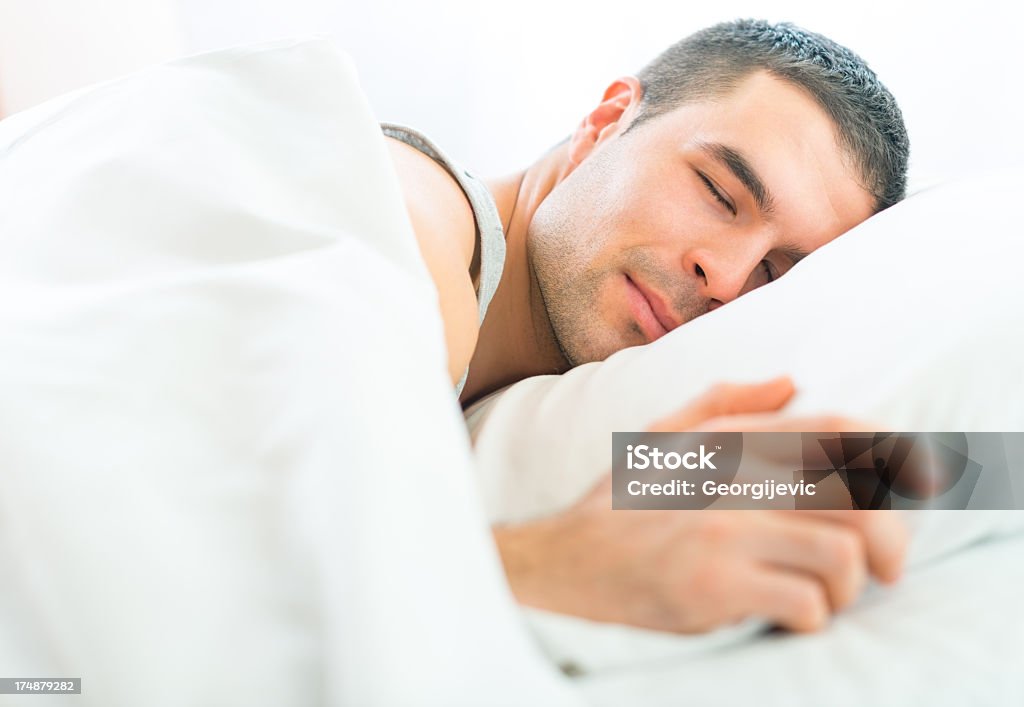 Attraente giovane uomo di dormire in un letto morbido fogli - Foto stock royalty-free di Adulto