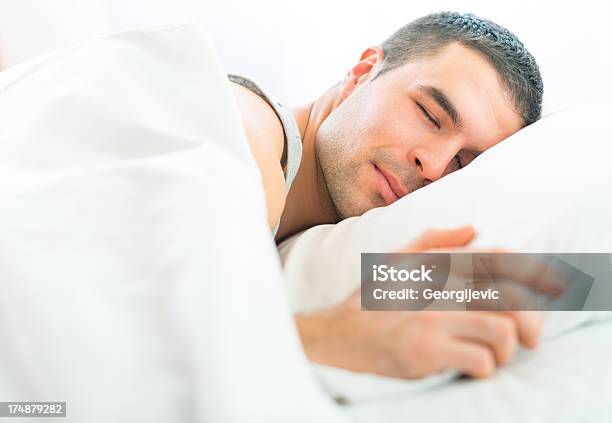 Foto de Atraente Jovem Dormindo Em Uma Cama Macia E Lençóis e mais fotos de stock de Adulto