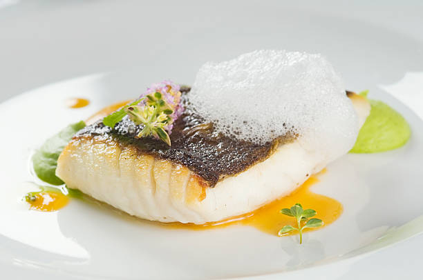 Baked turbot fillet on a white plate Baked turbot fillet with herbs and served with pea puree. Shallow dof. turbot stock pictures, royalty-free photos & images