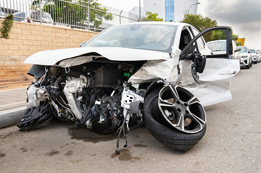 Rishon Lezion, Israel - October 10, 2023. Front part of a white car wrecked in an accident with a wheel torn off on the road