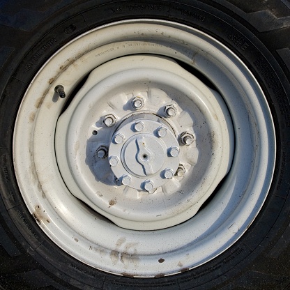 The white steel wheel design of a truck. Black truck tire and dirty white steel rim for use in design or backgrounds.