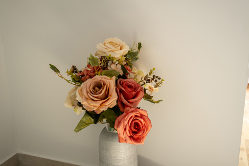 flower arrangement on table. Bouquet of roses in a paper box. vase in the background.