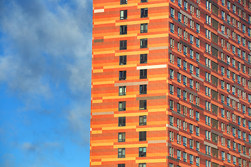 glazed facade of a high-rise building against a blue sky with clouds