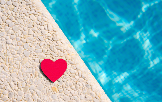A red heart lies on the edge of the pool. Good summer holiday concept