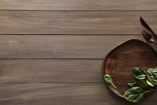 Food photography. Fresh basil, board and cutlery on wooden table, flat lay with space for text