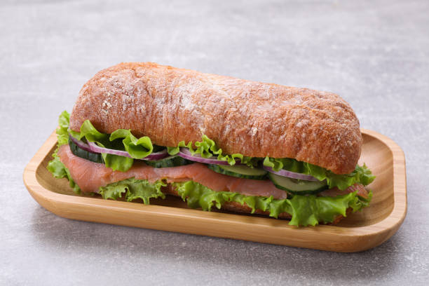 istock Delicious sandwich with fresh vegetables and salmon on light gray table 1748934345