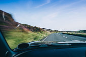 Sports car speeds over the mountain road on the Isle of Man in the summer