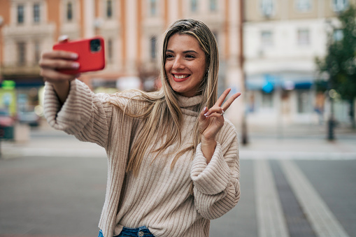 Beautiful young woman taking selfie on the street.