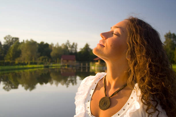 Young beautiful woman sits on wooden bridge and plays with water