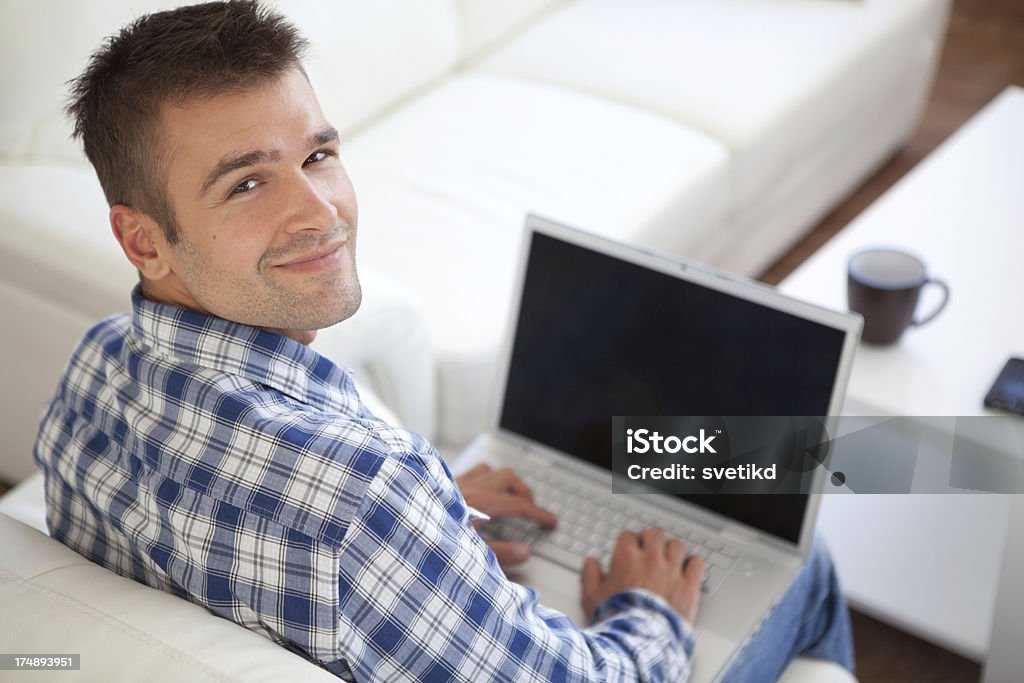 Young men with laptop. Young men working on laptop looking at camera. High angle view.See more images of this handsome male MODEL. Click on image below for lightbox. 20-29 Years Stock Photo