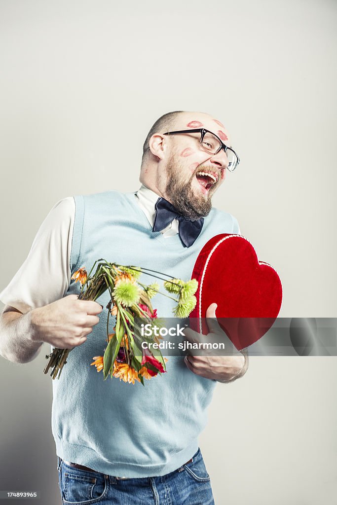 Humorous Man covered in Kisses and holding Bouquet of Flowers A nerdy man covered in red lipstick kisses holding a colorful bouquet of flowers and red heart. Men Stock Photo