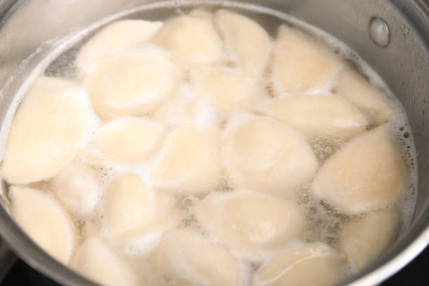 Cooking dumplings (varenyky) with cottage cheese in pot, closeup