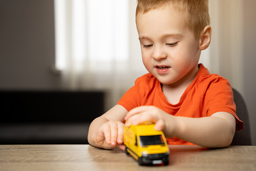 Cute toddler boy playing with a toy yellow car. Children's leisure and lifestyle. Childhood. Focus on the child.