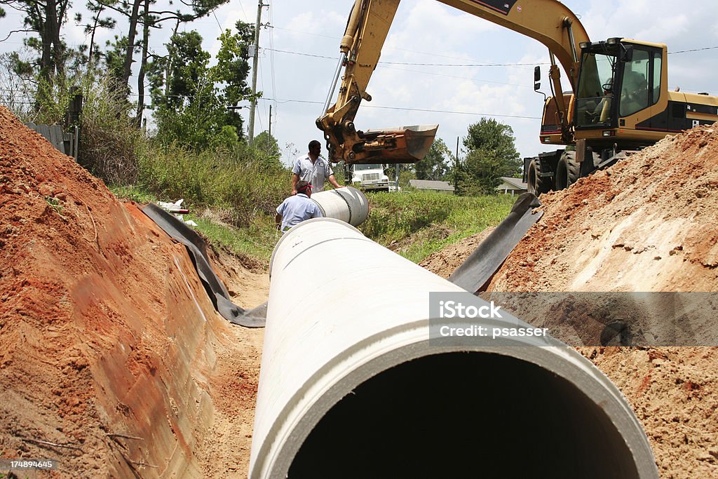 Road Work A culvert is being installed in a roadside ditch. No recognizable faces are visible. Sewer Stock Photo