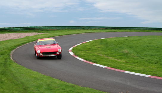 A red classic sports car taking a corner on the track.Other pics in this series: