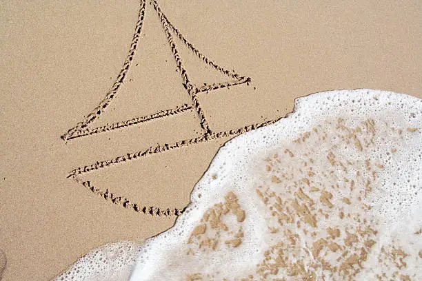 Sailing boat on the wave drawn in the sand
