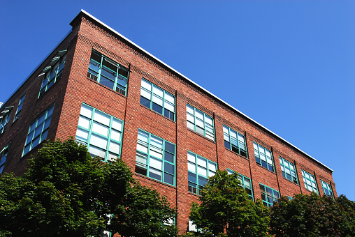 An old building sprouts up from the trees in Seattle, WA. From the outside it apperas to be artist lofts and work spaces. 