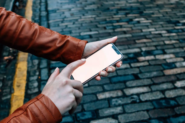 istock Woman's hand Holding small modern smartphone on Cobblestone Street UI Mock Up - Using Index Finger Side on 1748961558