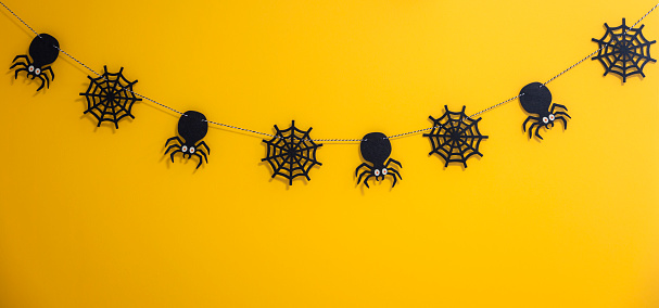 Halloween accessories spider and spider web on yellow background.The concept of celebrating Halloween Days