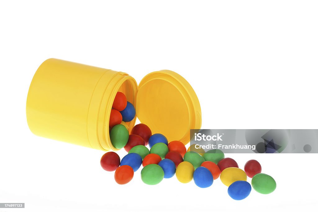 Colorful Chocolate-covered Peanuts slipping from a bottle Blue Stock Photo