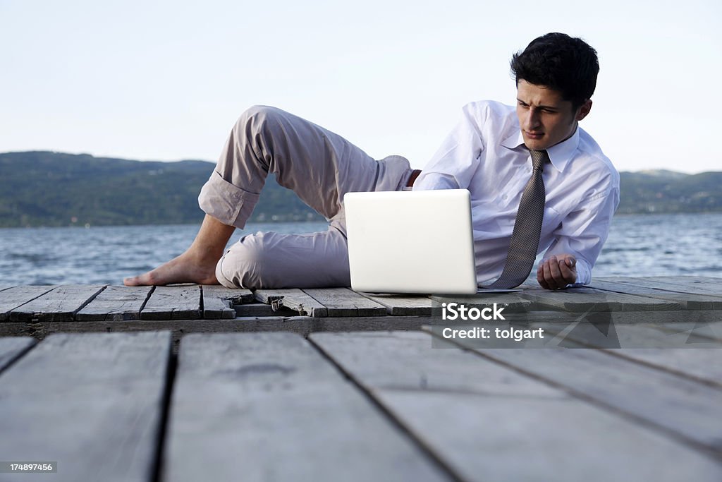 Uomo su un molo al lavoro all'aperto - Foto stock royalty-free di Computer portatile