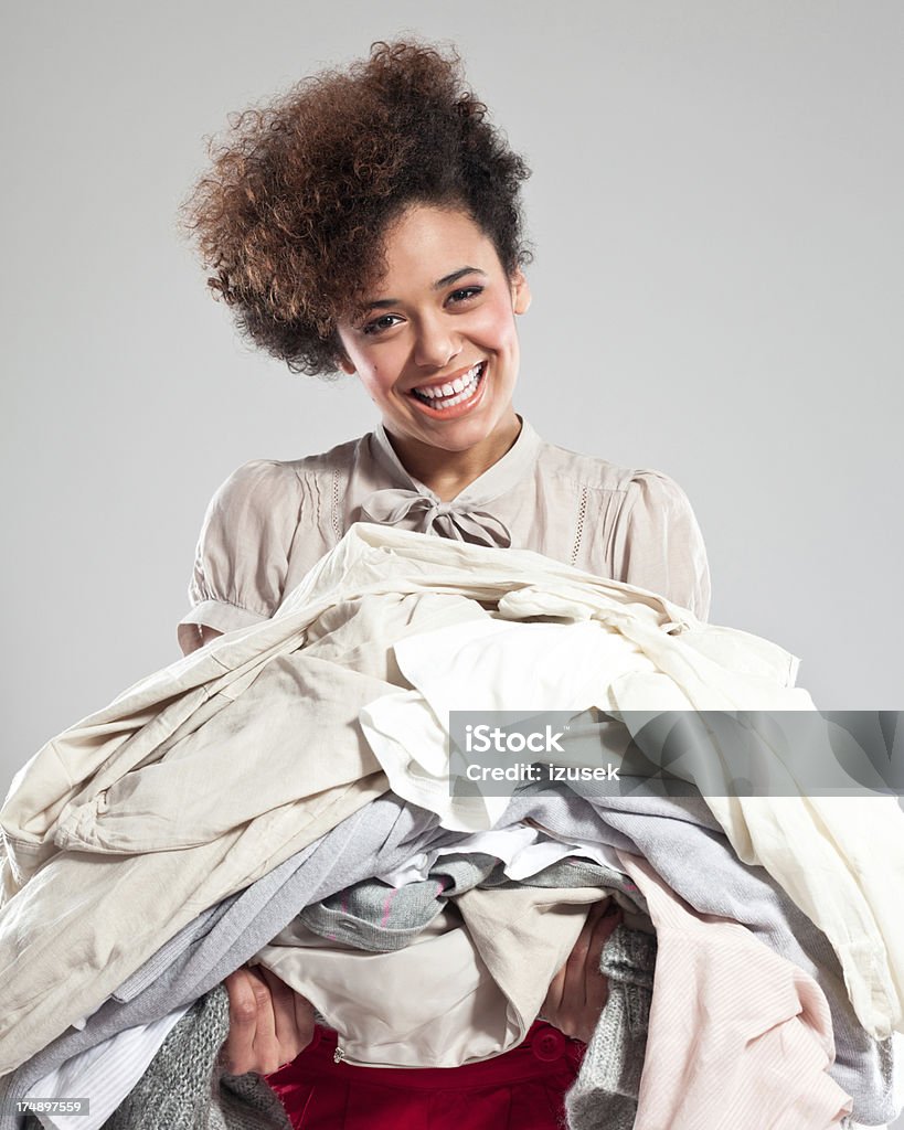 Happy Young Woman carrying clothes Portrait of beautiful teenaged afro girl carrying a pile of clothes and laughing at the camera. 18-19 Years Stock Photo