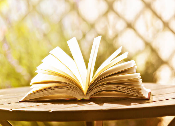 istock Lots to learn! Book lies open on garden table 174898272
