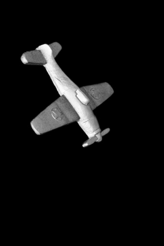 Toy airplane replica in die-cast metal, simulating a kamikaze dive-bombing raid, isolated on black.