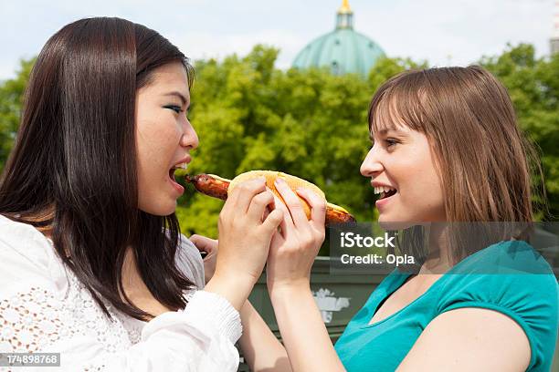 Two Young Women Sharing A Sausage Roll Stock Photo - Download Image Now - 20-24 Years, 20-29 Years, 25-29 Years