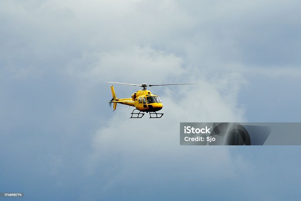 Giallo elicottero volare nel cielo nuvoloso - Foto stock royalty-free di Aeronautica