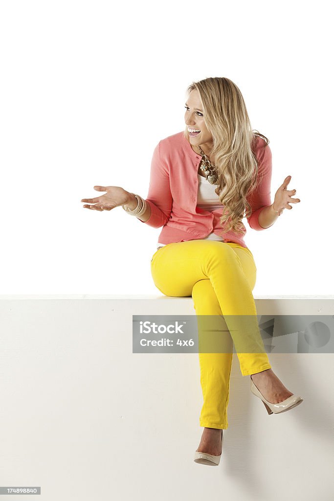 Sonriente Joven mujer sentada en la bandeja de pared - Foto de stock de 20 a 29 años libre de derechos