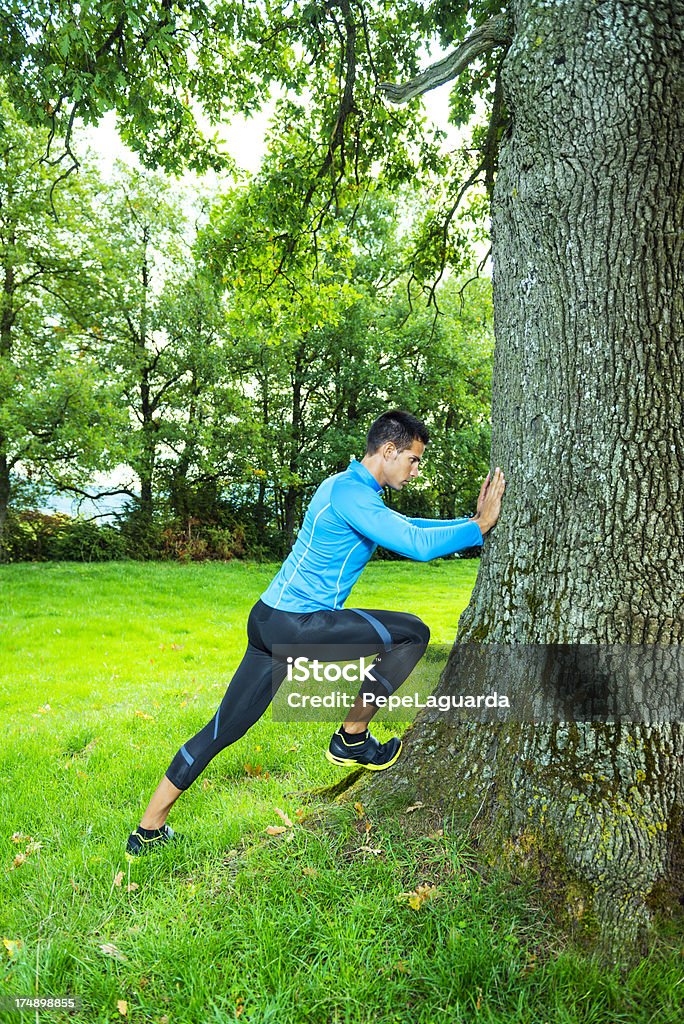 Uomo lo stretching i muscoli dopo jogging all'aperto - Foto stock royalty-free di Correre