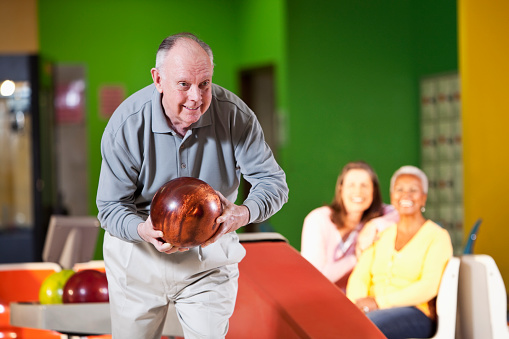 Close up photo of bowling balls while two people are playing bowling in the background.