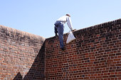 Close-up of a thief climbing over a brick wall