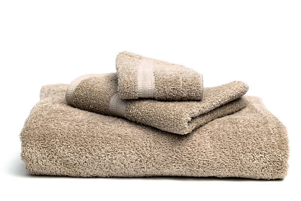 A pile of brown bath towels on a white background Bath towel, hand towel and washcloth set terry towel stock pictures, royalty-free photos & images