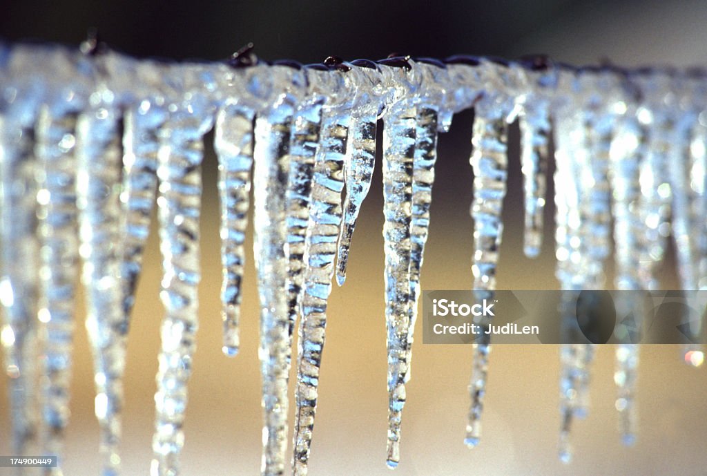 Pingentes de gelo de frozen em uma cerca de malha de arame - Foto de stock de Fileira royalty-free