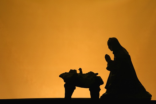 Nativity scene with Mary and baby Jesus in silhouette on gold background with copy space. Horizontal image would be good for Christian or religious Christmas use.