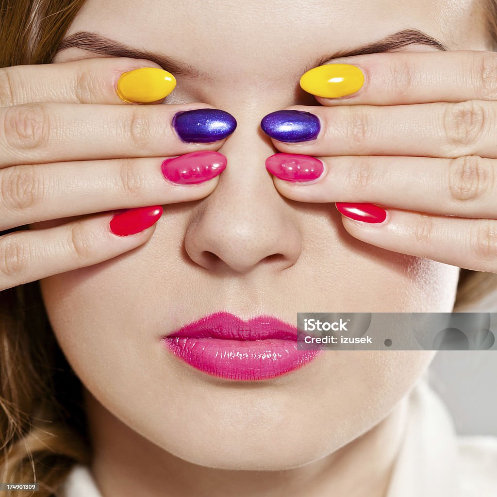 Multicolored manicure Close up of young woman covering her eyes by hands with multicolored manicure. Studio shot. Human Face Stock Photo