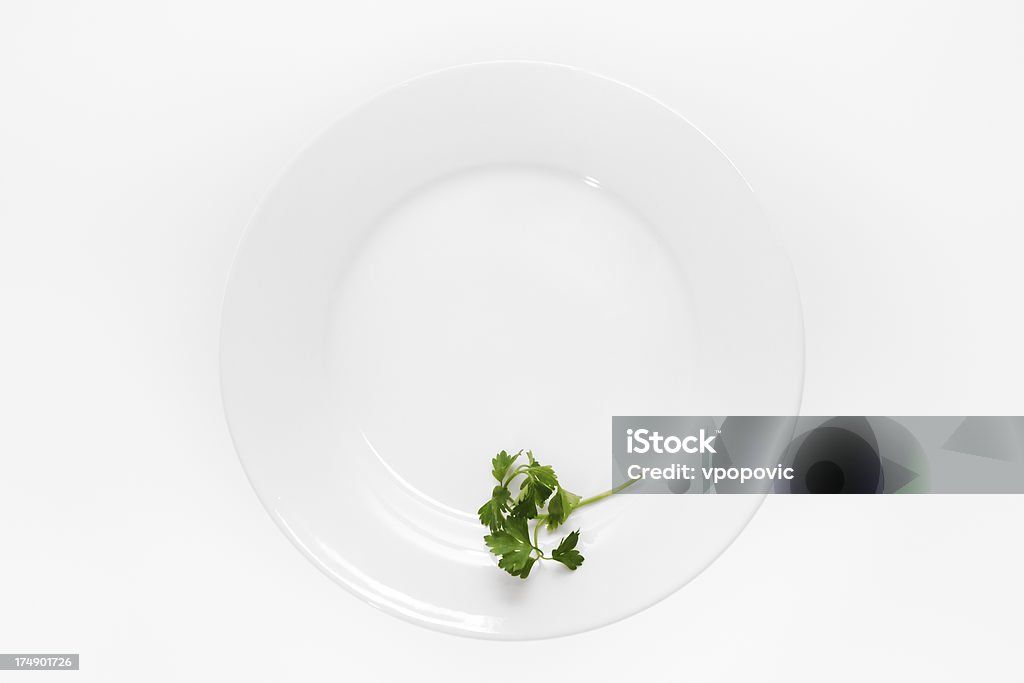 Diet Time "Parsley leaf on white ceramic plate on white background (high key photo). Conceptual photo of body weight control, low calories food, time for a diet, anorexia, ... More images in" Garnish Stock Photo
