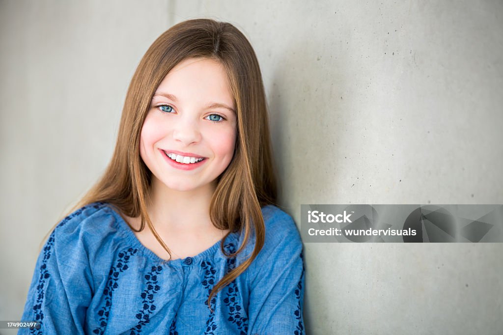 Garota sorridente encostando contra parede, olhando para a câmera - Foto de stock de 10-11 Anos royalty-free