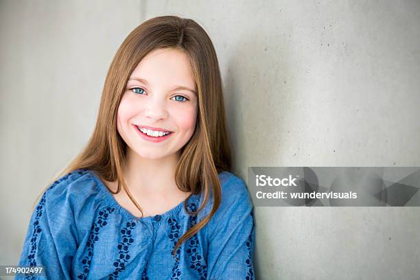 Foto de Garota Sorridente Encostando Contra Parede Olhando Para A Câmera e mais fotos de stock de 10-11 Anos