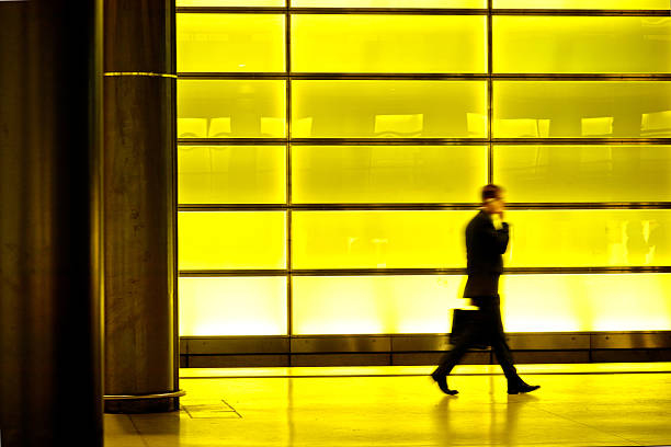 blurred businessman walking in a modern subway station with mobile