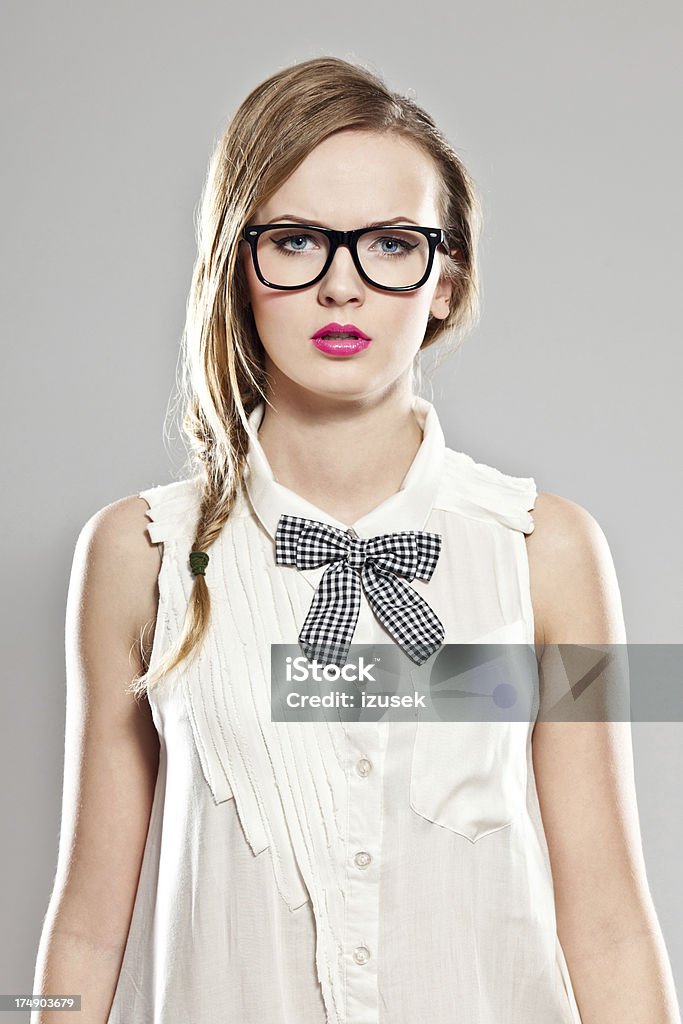 Female student "Portrait of young woman wearing glasses, standing against grey background and looking at the camera." 20-24 Years Stock Photo