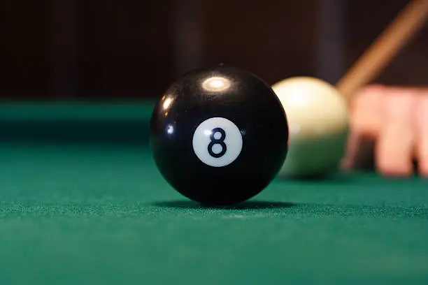 "Focus on the 8 ball, about to be hit and sunk into the corner pocket.  The corner pocket, the point of view for the photograph."