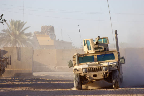 Military humvee driving through desert like conditions View of Armored HMMWV in Iraq. armored vehicle photos stock pictures, royalty-free photos & images