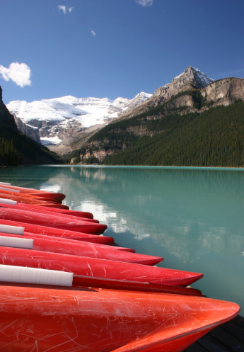 The bottoms of red boats on the shore of a pristine mountain lake.