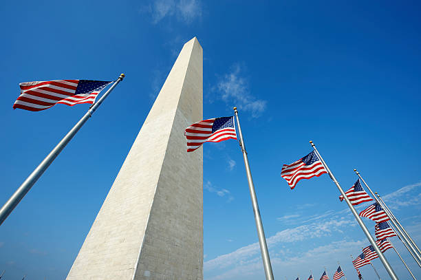 Washington Monument American Flags Blue Sky American flags ring the Washington Monument in Washington DC under a bright blue sky national monument stock pictures, royalty-free photos & images