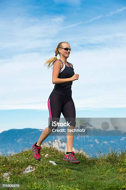 Hermosa Mujer Joven Corriendo En La Montañas Foto de stock y más banco de imágenes de 20-24 años - 20-24 años, Actividad, Actividad física