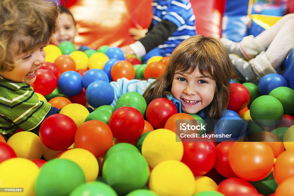 Children playing in the ball pool Happy playful kids enjoying while playing the the pool of balls. Ball Pool Stock Photo